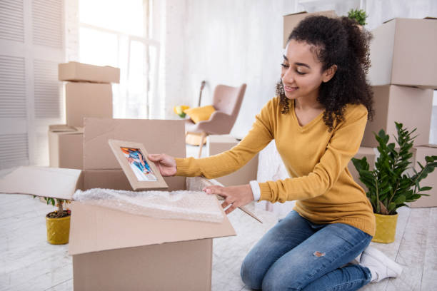 istock Pleasant curly-haired girl packing framed photo before moving out 962088912