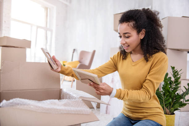 istock Curly-haired girl looking through framed photos while packing 962088958