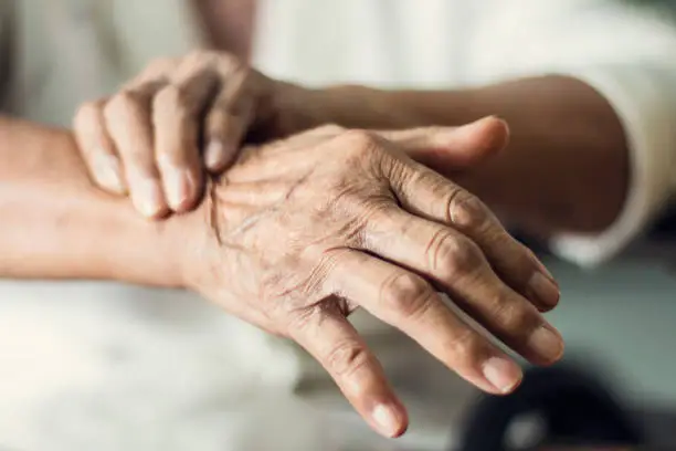 Photo of Close up hands of senior elderly woman patient suffering from pakinson's desease symptom. Mental health and elderly care concept