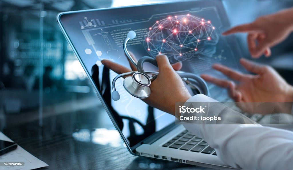 Medicine doctor team meeting and analysis. Diagnose checking brain testing result with modern virtual screen interface on laptop with stethoscope in hand, Medical technology network connection concept. Healthcare And Medicine Stock Photo