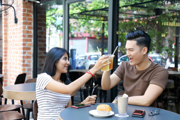 istock Young Asian man woman cheers drinks glasses 962103224