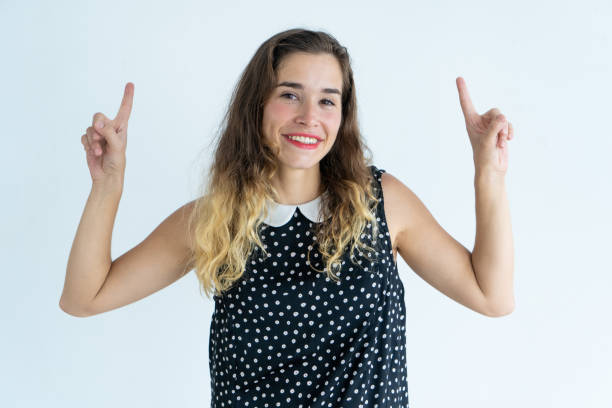 istock Smiling beautiful young woman pointing upwards 962107346