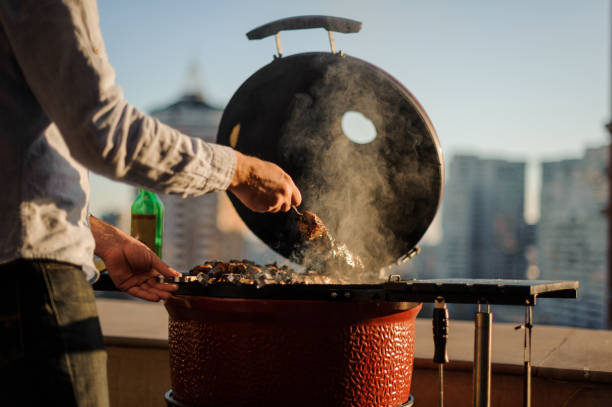 mann, kochen eine gericht in einem barbecue-grill mit kochen werkzeuge stehen auf dem dach ausgestattet - barbecue chicken fotos stock-fotos und bilder