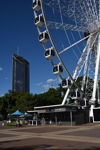 Wheel of Brisbane ferris wheel in South Bank precinct, with 1 William Street government office building in background.