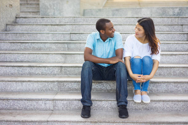 istock Smiling mixed race man and woman sitting at talking on staircase 962113182