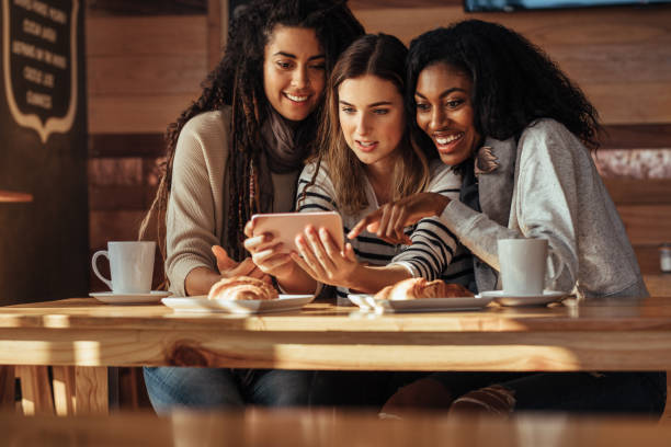 istock Friends sitting in a cafe looking at mobile phone 962119690
