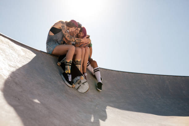 istock Women skaters using mobile phone at skate park 962123010