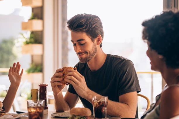 istock Man eating burger with friends at restaurant 962123278