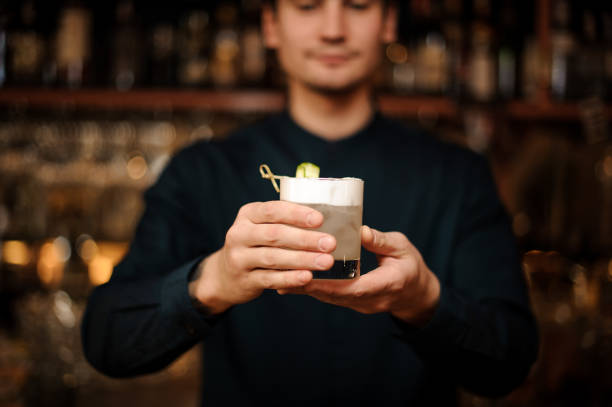 istock Young barman holding a glass filled with 962125616