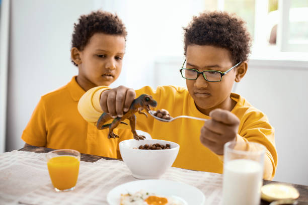 istock Cute little boy watching his brother feed toy dinosaur 962134666