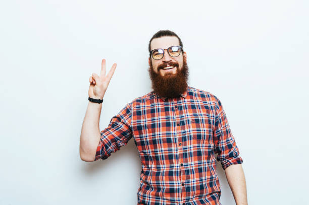 istock Happy smiling man with beard and eyeglasses showing two fingers, peace gesture 962134966