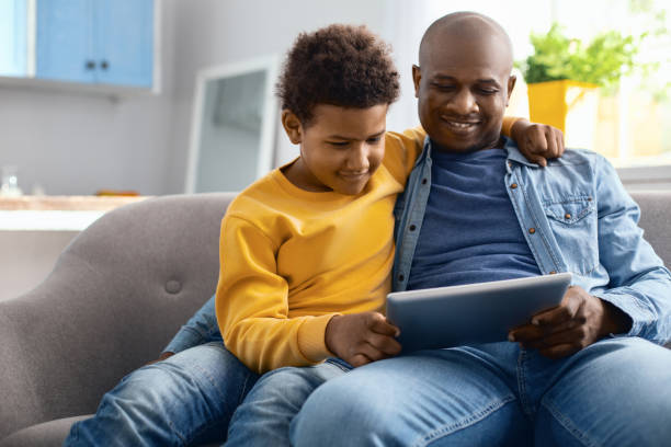 istock Cheerful father and son watching videos on tablet 962145556