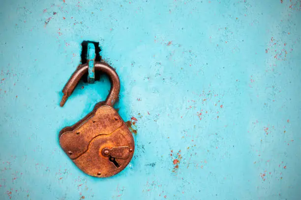 Old rusty lock without a key on a blue background.