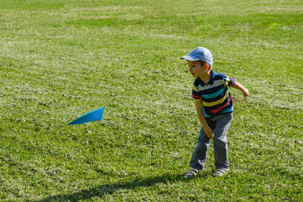 istock Boy playing with a blue toy plane at park on a sunny day 962150374