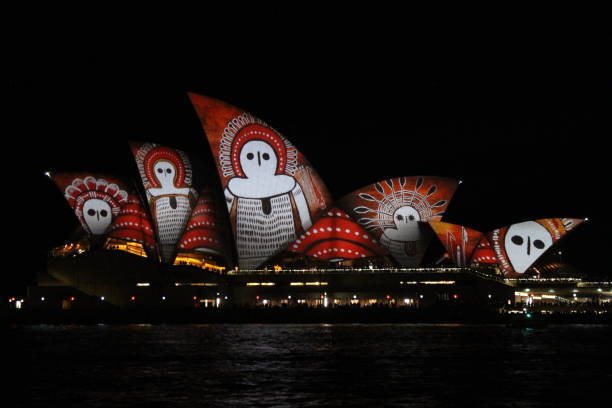 The Sydney Opera House at night with bright projections on its surfaces during the Vivid Festival. In 2016 the inspiration was Aboriginal art.