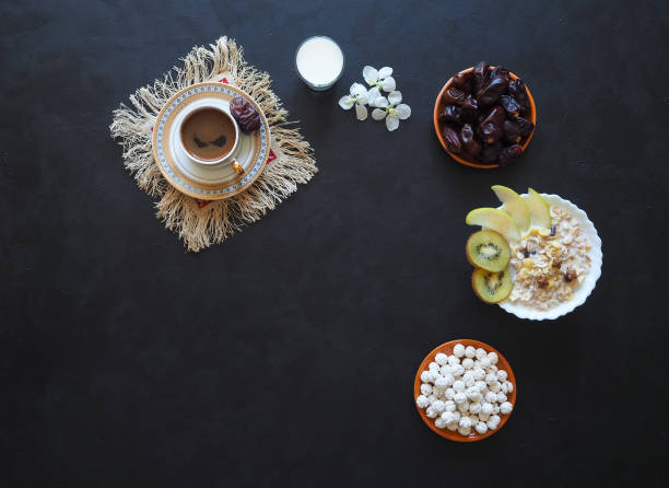 istock Breakfast with muesli on black background. Black coffee with Turkish sweets, muesli, dates and milk. Sweet food for Ramadan. 962151498