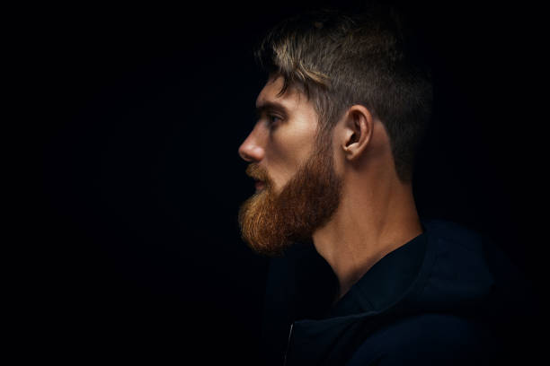 istock Close-up image of serious brutal bearded man on dark background 962157250
