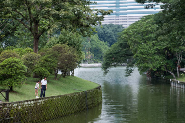 A young girl fishes with her grandfather in the lake at the public park
