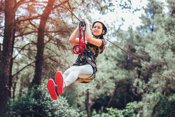 Happy school girl enjoying activity in a climbing adventure park on a summer day Happy school girl enjoying activity in a climbing adventure park on a summer day canopy tour photos stock pictures, royalty-free photos & images