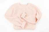 Pink knit sweater flat lay on white background.