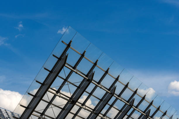 Detail of steel and glass roof of a modern building with blue sky and clouds