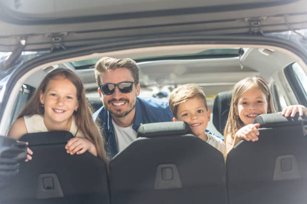istock Three adorable kids sitting in a trunk car with father 962157928