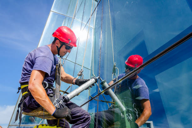 View on applying silicone sealant with gun on joints between windows Industrial climber is applying silicone to rubber juncture among building glass facade. sealant photos stock pictures, royalty-free photos & images
