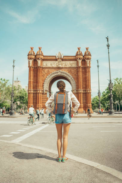 женщина смотрит на триумфальную арку в барселоне - barcelona стоковые фото и изображения