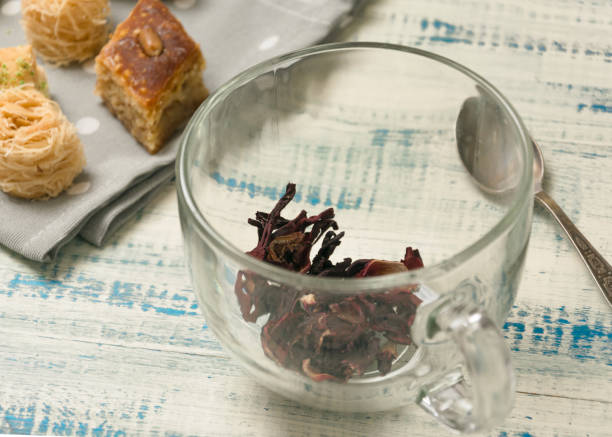Preparation for tea. Dry tea in a cup on a background of oriental sweets on a wooden background.