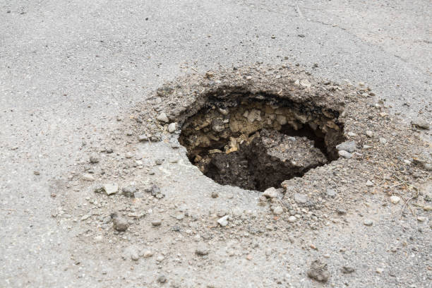 istock Big, deep hole on the asphalt road. Dangerous, bad automobile driveway. Damaged surface. 962167468