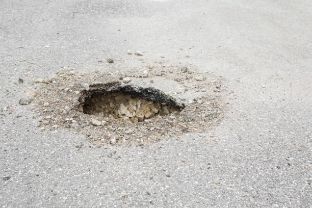 istock Big, deep hole on the asphalt road. Dangerous, bad automobile driveway. Damaged surface. 962167566
