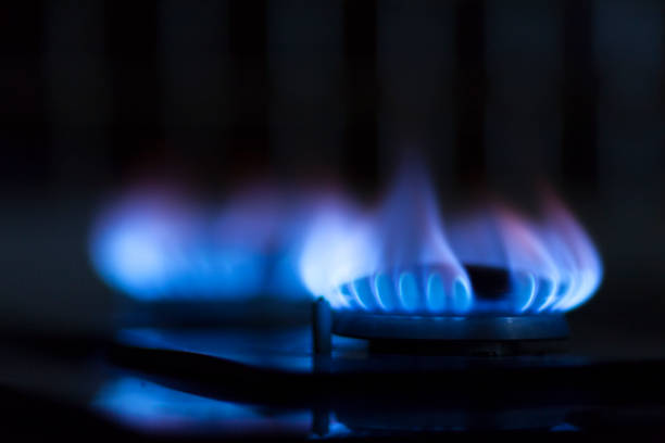 A gas stove burner with a bright blue flame, glowing against a dark backgroundA gas stove burner with a bright blue flame, glowing against a dark background