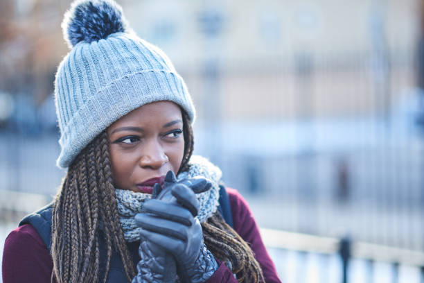 dressed for warmth when the temperature drops - braids african descent women pensive imagens e fotografias de stock