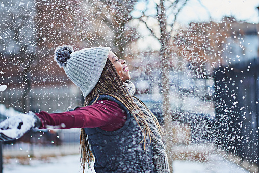 Portrait of two happy boys brothers in winter sport outfit play with snowman in Santa hat and scarf outside