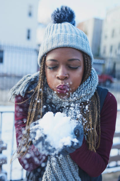 Shot of a beautiful young woman blowing a snowball on a wintery day outdoors