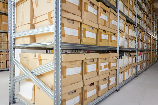 Stacks of files and paperwork placed in bookshelves with folders and documents in cardboard box archive, storage room.