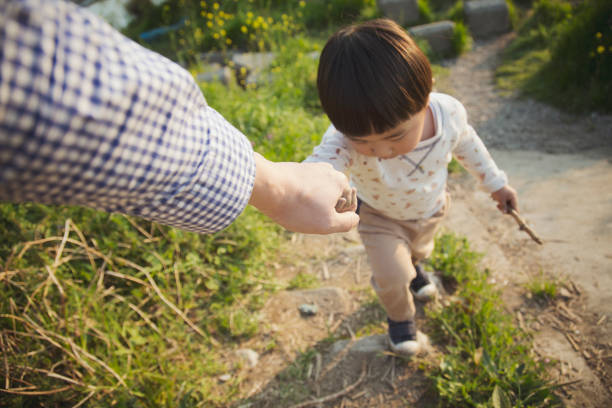 Hand of asian father and his son walking together with holding each other's hands.