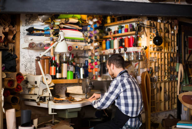 istock male worker sewing stitches on belt in leather workshop 962174398