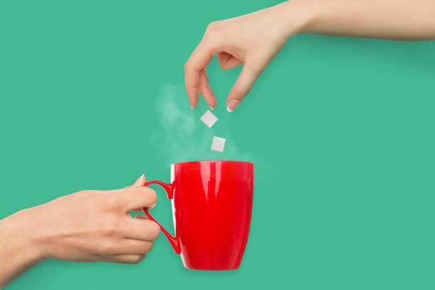 istock Woman hand putting sugar in red coffee cup 962179664