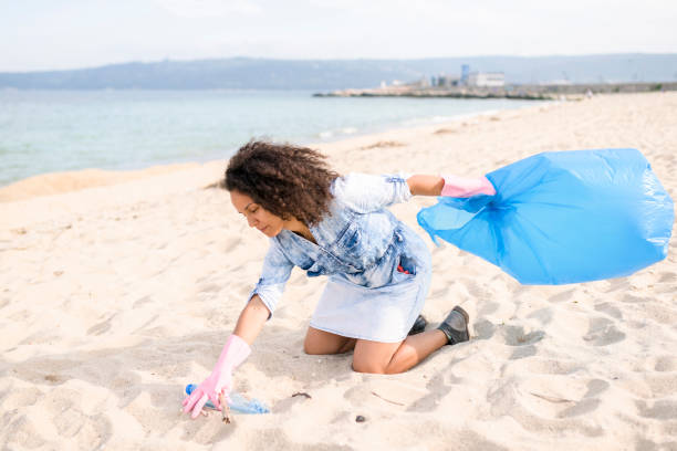 istock Pretty young woman picking up garbage during local clean up 962181864