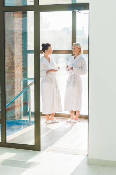 istock beautiful young women in bathrobes drinking coffee at spa center 962181890