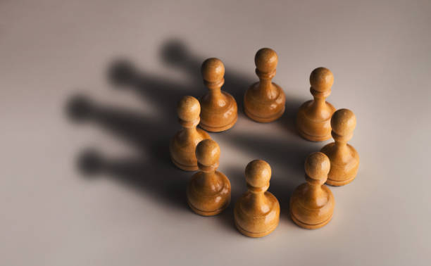 Chess pawn circle with shadow shaped as crown Wooden chess pawn circle with shadow shaped as crown on gray background. Teamwork, group agreement and success concept coalition photos stock pictures, royalty-free photos & images