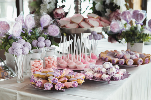 Pink candy bar for holiday celebration. Sweet buffet for birthday party or wedding. Desserts assortment against wooden background, catering concept