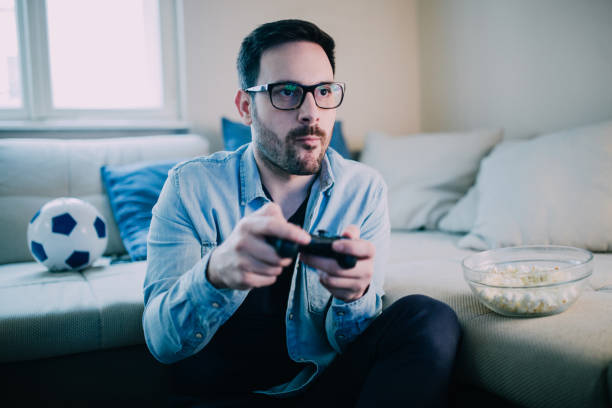 istock Young man eating and playing video games 962190272