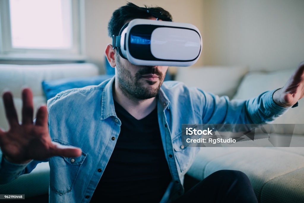 Serious man wearing virtual reality glasses Young man wearing virtual reality simulator Eyeglasses Stock Photo