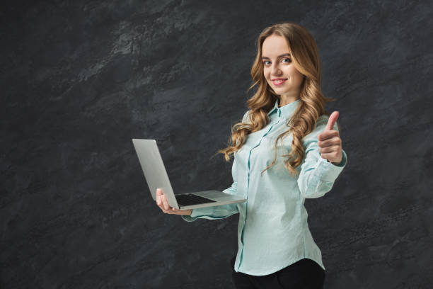 istock Happy woman with laptop on gray background 962192858