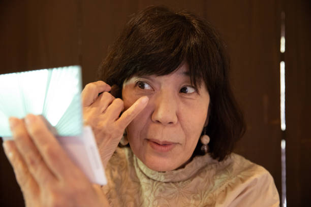 ältere frau putting make-up - sakyo stock-fotos und bilder