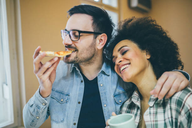 istock Couple hugging, man eating pizza and woman holding coffee cup 962199220