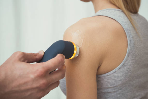 Physiotherapist performing ultrasound therapy of the shoulder stock photo
