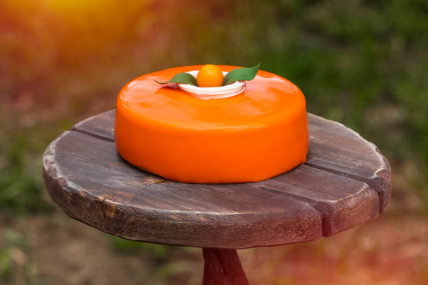 Cake with orange mousse and almond krokantom in the mirror glaze, on a wooden tray